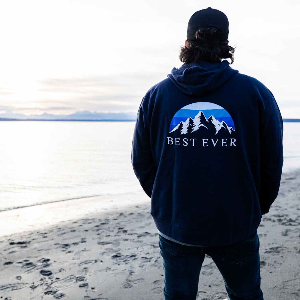 Man staring at mountains wearing best ever mountain calling hoodie